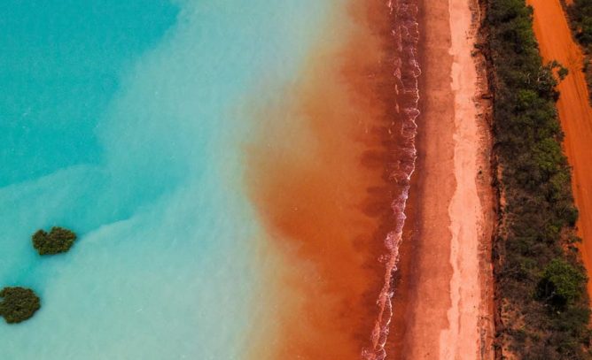 Red dirt road meets turquoise water