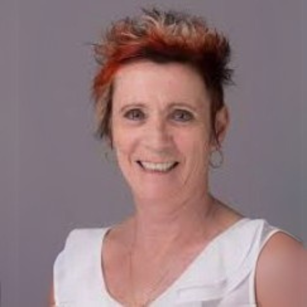 A smiling woman with short spiky hair in a white sleeveless top