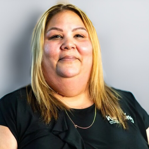 A woman with shoulder-length blonde hair wearing a black t-shirt and a silver chain.