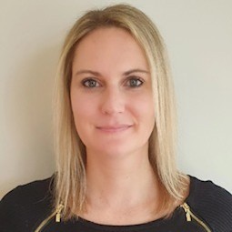 A woman with blonde hair wearing a black top, smiling at the camera.