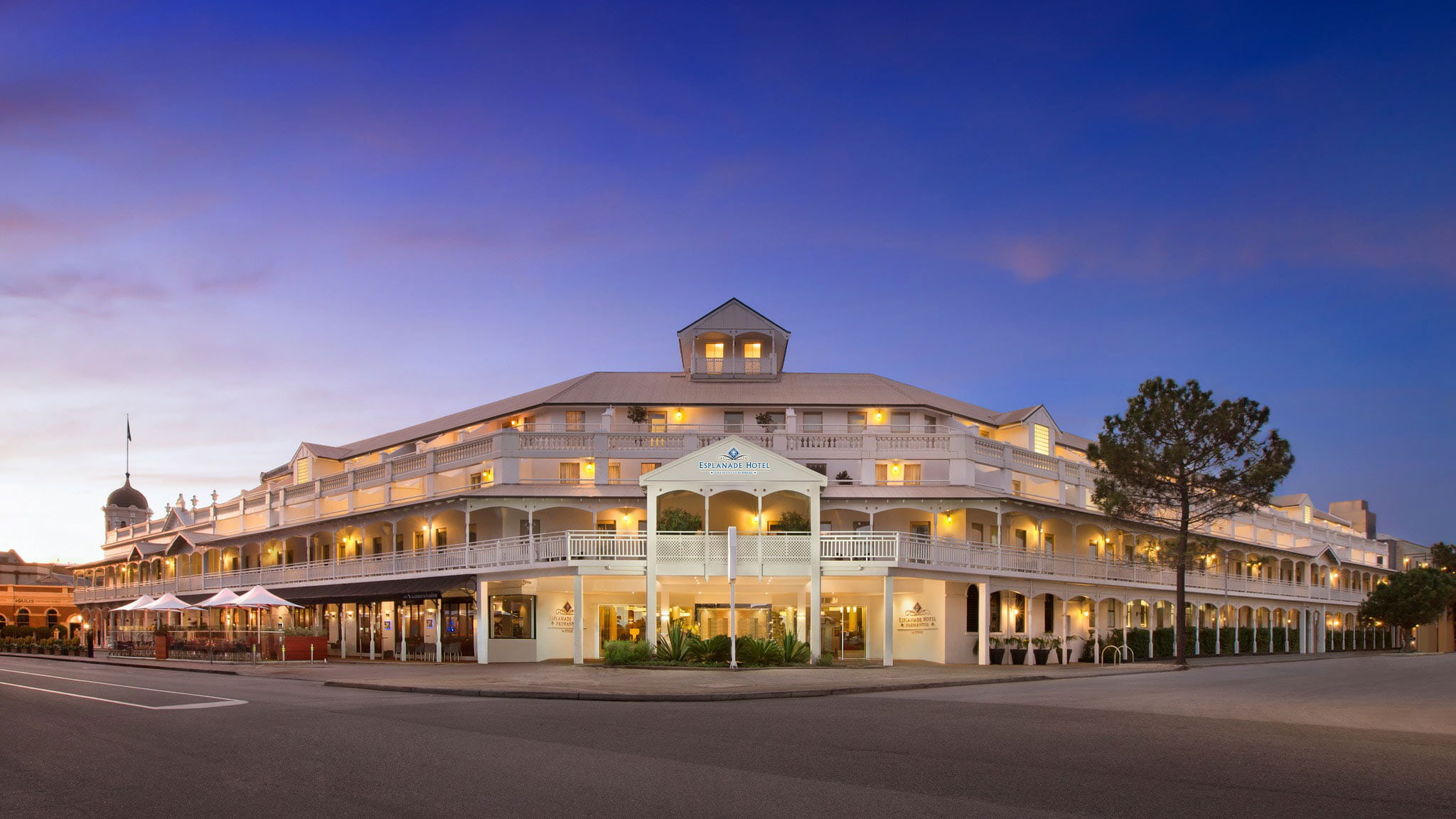 A two -storey building with verandah and balcony on a street corner at dusk.