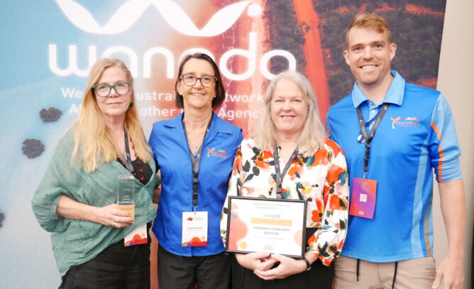 Four smiling individuals stand in front of the WANADA media wall, holding their certificate and trophy at the WA Alcohol and Other Drug Excellence Awards.