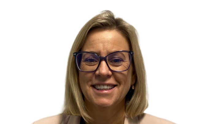 Woman with shoulder length blonde hair wearing glasses, a pendant, and white jacket over a black top.