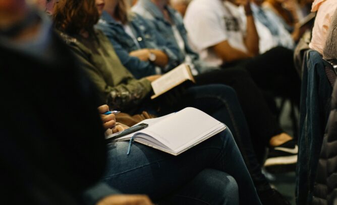 People seated in a room holding open books on their laps.